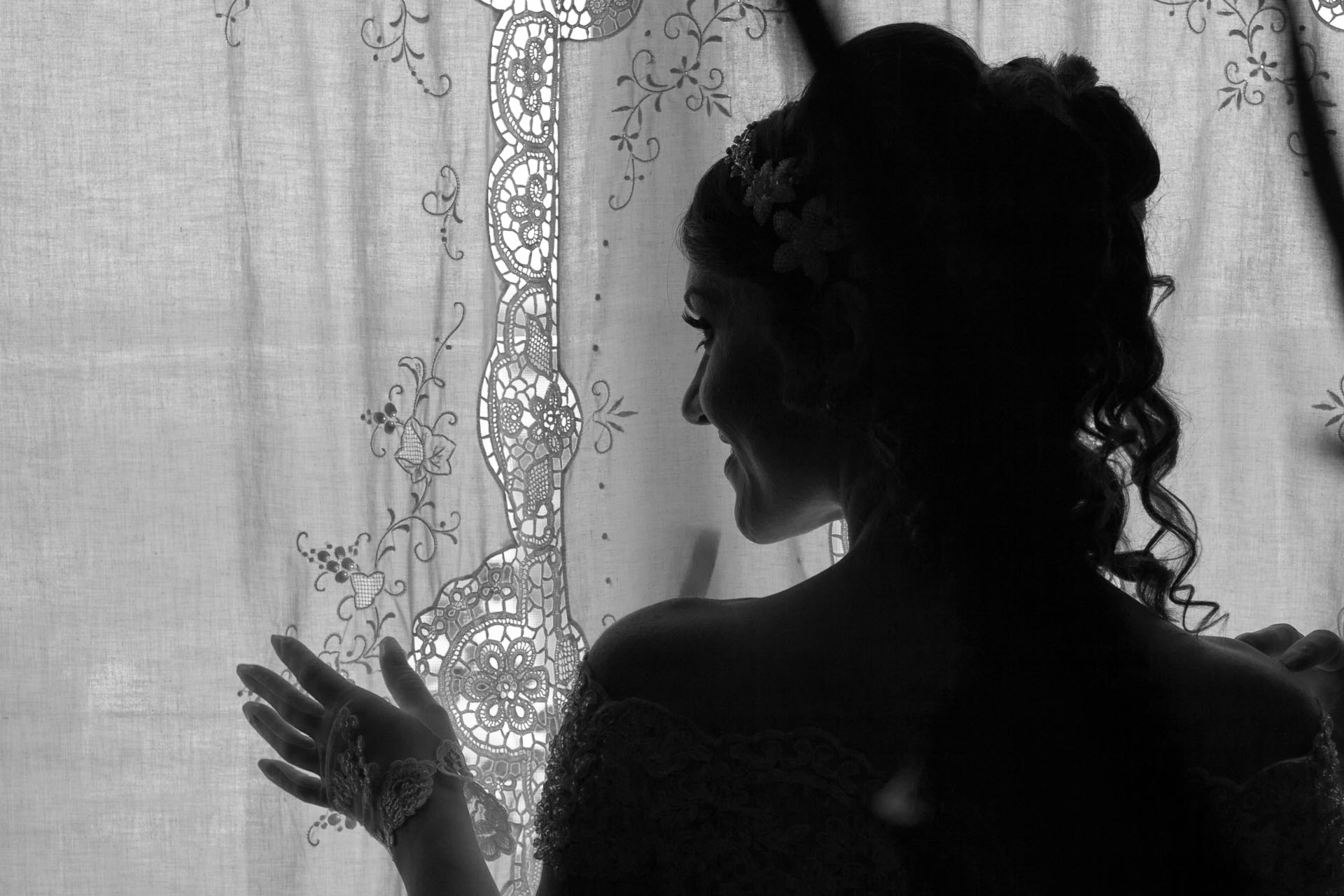 Ritratto di spalle in silhouette della sposa dietro la tenda di una finestra